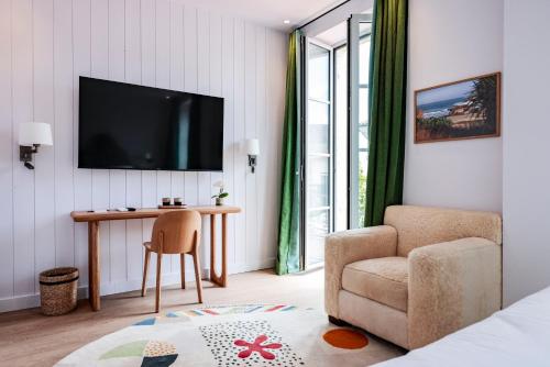 a room with a chair and a table and a television at Hotel du Balcon in Capbreton
