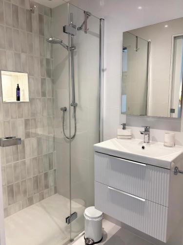 a white bathroom with a shower and a sink at Headland View Boutique B&B in Torquay