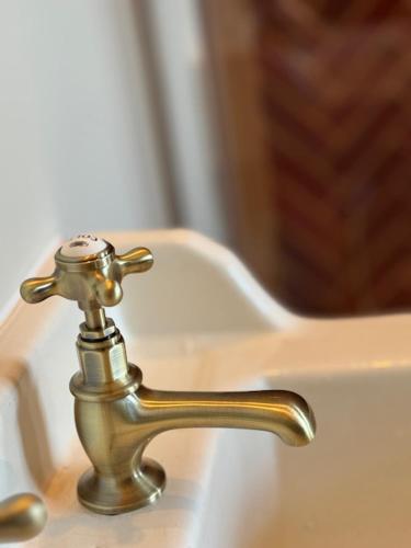 a bathroom sink with a brass faucet at Chambre d'hôtes Villa Calys in Claira