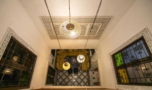 a chandelier hanging from a ceiling in a room with windows at Riad Dar Jnan Sbil in Fès