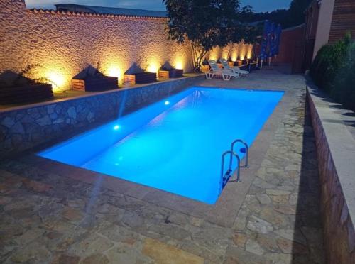 a swimming pool with blue lighting in a backyard at night at Planinske Kuće Grocka in Grocka