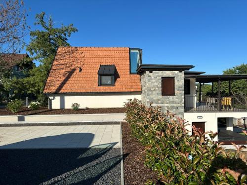 a house with an orange roof and a patio at Csipetnyi Chill Vendégház in Óbudavár