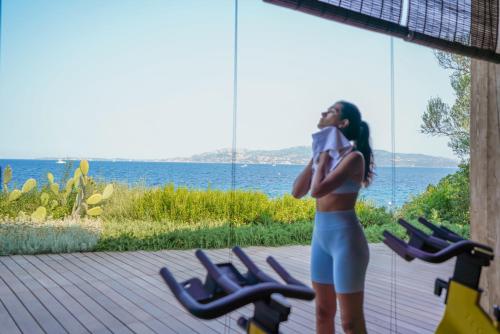 a woman talking on a cell phone next to the ocean at Hotel Capo d'Orso Thalasso & SPA in Palau