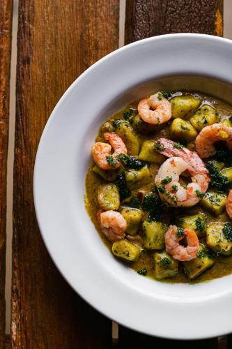 a bowl of shrimp and vegetable soup on a wooden table at Ilha do Mel Lodges in Ilha do Mel
