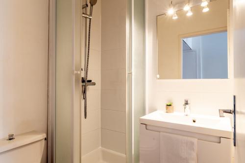 a white bathroom with a sink and a shower at Le Raffiné - Studio avec balcon, proche de l'océan in La Baule