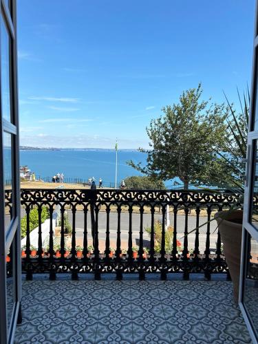 a bench on a balcony with a view of the water at Headland View Boutique B&B in Torquay