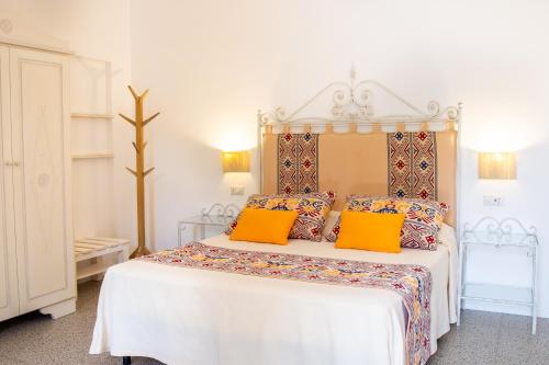 a bedroom with a white bed with orange pillows at Agriturismo La Genziana in Alghero