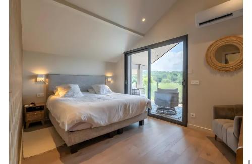 ein Schlafzimmer mit einem Bett und einem großen Fenster in der Unterkunft Villa proche Lac in Écharvine