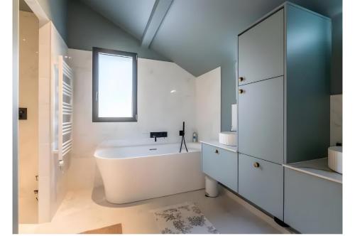ein Bad mit einer weißen Badewanne und einem Fenster in der Unterkunft Villa proche Lac in Écharvine