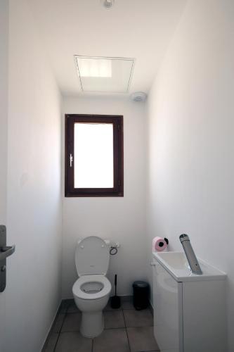 a white bathroom with a toilet and a window at Welcome Home in Vert-le-Grand