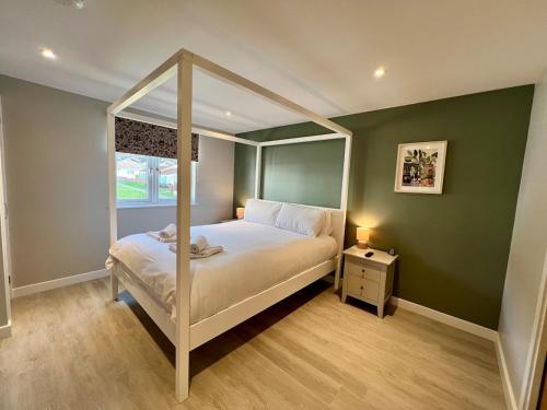 ein Schlafzimmer mit Himmelbett und Fenster in der Unterkunft Stylish 3-Bed Seaview Retreat with Balcony - Steps from the Beach - Westward Ho! in Westward Ho