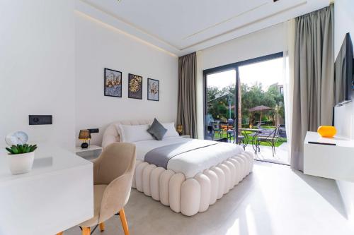 a white bedroom with a large white bed and a desk at Villa Zahi in El Aïn