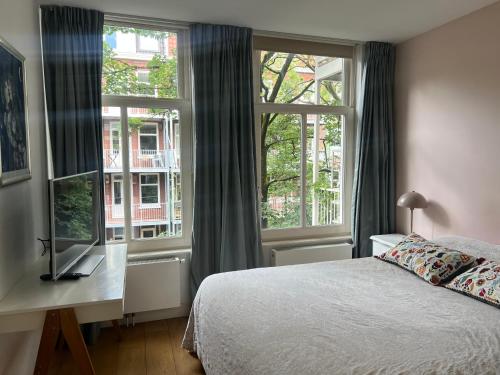 a bedroom with a bed and a desk and windows at Great Apartment Amsterdam in Amsterdam