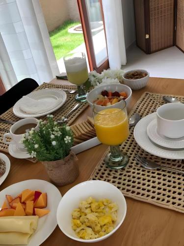 a table topped with plates and bowls of fruit and juice at Pousada Divino Milagre in Passo de Camarajibe