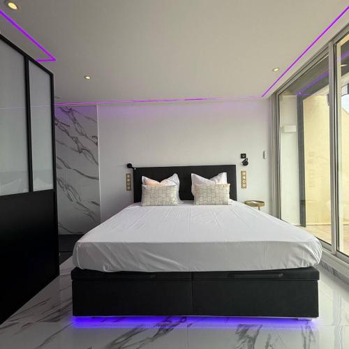 une chambre avec un grand lit avec un éclairage violet dans l'établissement Studio Luxe vue mer Persuasion - Héliopolis D 8 - 2 personnes, au Cap d'Agde
