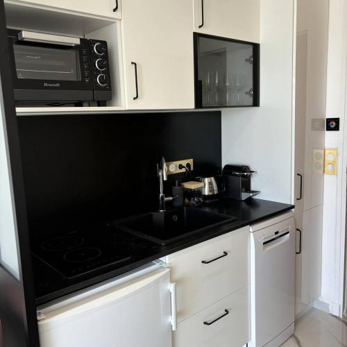 une cuisine avec un évier et un micro-ondes dans l'établissement Studio Luxe vue mer Persuasion - Héliopolis D 8 - 2 personnes, au Cap d'Agde