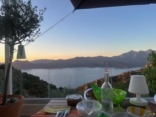 a table with a bottle of wine and a view of a lake at Casa Mimosa in Piana