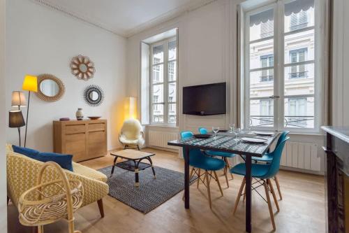 - un salon avec une table, des chaises et une télévision dans l'établissement Patchwork - Furnished apartment - Downtown Lyon, à Lyon