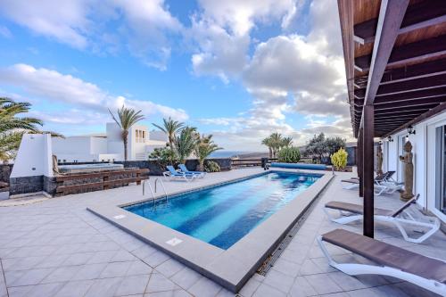 a swimming pool with lounge chairs next to a house at Princesa Calero in Puerto Calero