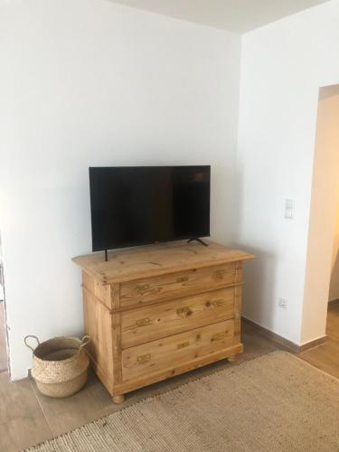 a flat screen tv sitting on top of a wooden dresser at Ländliche Fewo Wildblume, 4 km zum Stausee in Happurg
