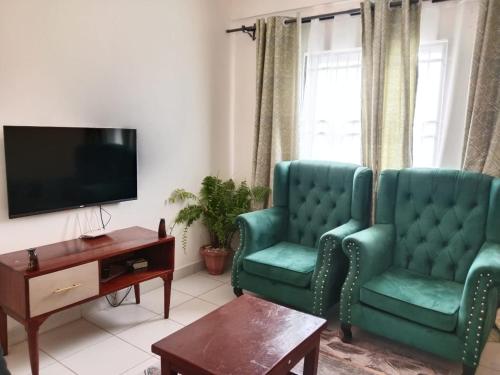 a living room with two green chairs and a tv at Buxton Point Kandy Epic Two Bedroom Apartments in Mombasa