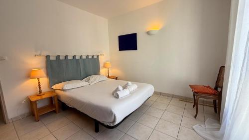 une chambre avec un lit blanc et deux chaises dans l'établissement Agréable maison proche plage, à La Couarde-sur-Mer