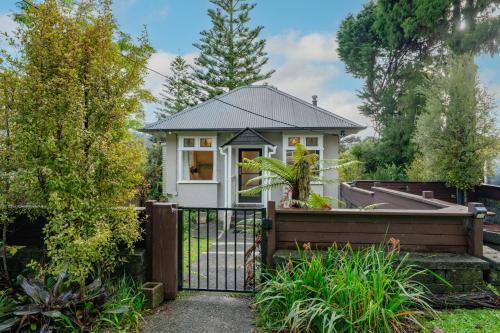 a house with a gate in a garden at Birdsong Retreat - Titirangi Holiday Home in Auckland