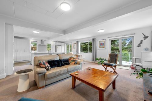 a living room with a couch and a table at Birdsong Retreat - Titirangi Holiday Home in Auckland