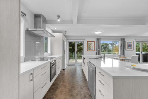a large kitchen with white counter tops and appliances at Birdsong Retreat - Titirangi Holiday Home in Auckland