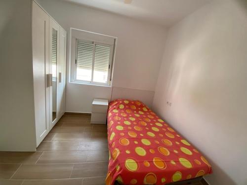 a small bedroom with a red bed with a window at Beachside Getaway in Zapillo in Almería