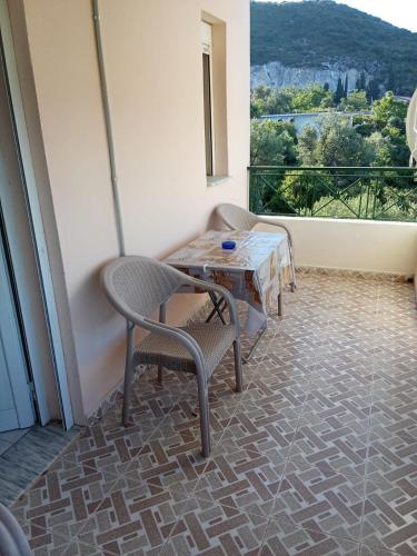 a balcony with a table and chairs and a window at Roland Apartments in Dhërmi