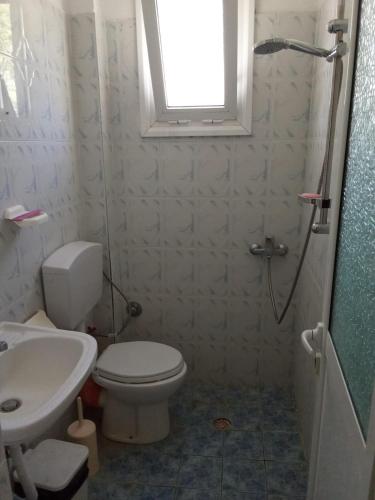 a bathroom with a toilet and a sink and a window at Roland Apartments in Dhërmi