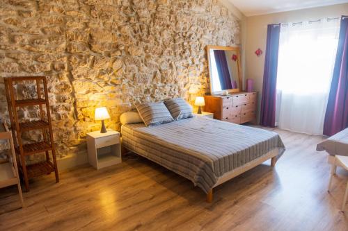 a bedroom with a bed and a stone wall at La Barbacane in Sigean