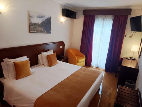a hotel room with a bed and a chair at Hotel Turismo Miranda in Miranda do Douro