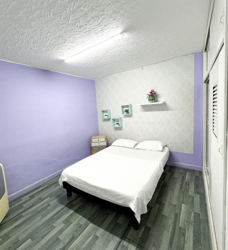 a bedroom with a white bed and purple walls at Hostal Santiago DC in Cali