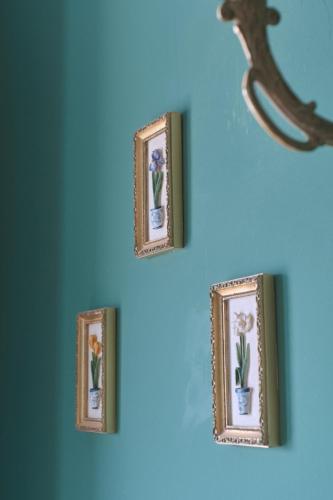 a group of framed pictures on a blue wall at Castell Granadella in L'Ampolla