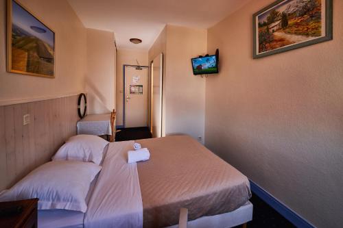 a hotel room with two beds and a tv on the wall at La Caravelle in Riom