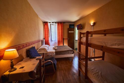 a room with two bunk beds and a table with a lamp at La Caravelle in Riom