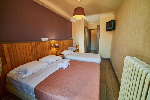 two beds in a hotel room with a stuffed animal on the bed at La Caravelle in Riom