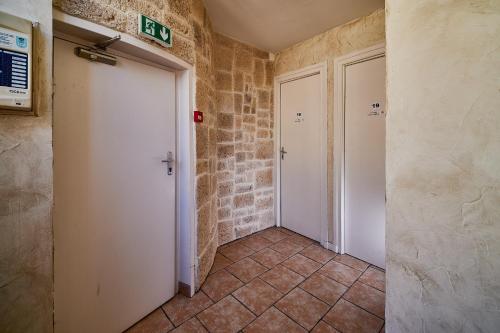 a hallway with two white doors and a brick wall at La Caravelle in Riom