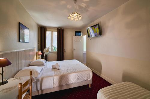 a bedroom with two beds and a tv on the wall at La Caravelle in Riom