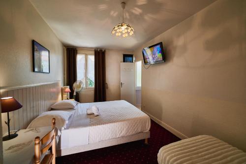 a bedroom with two beds and a tv on the wall at La Caravelle in Riom