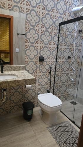 a bathroom with a toilet and a sink and a shower at Chácara Recanto dos Pássaros 04 in Olímpia