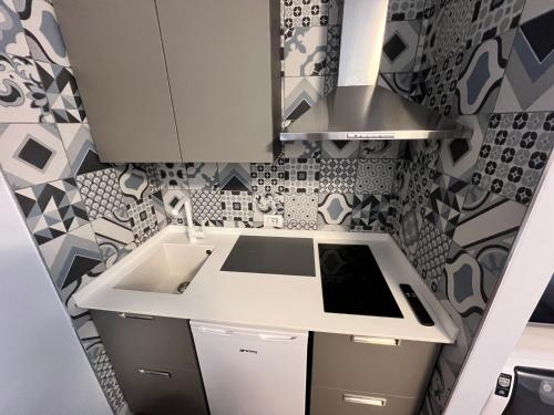 a kitchen with a white sink and a patterned wall at Aurora Boreale studio - centro Aprica - parking in Aprica