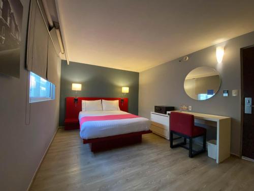 a hotel room with a bed and a desk and a mirror at Hotel MX forum buenavista CDMX, Trademark by Wyndham in Mexico City