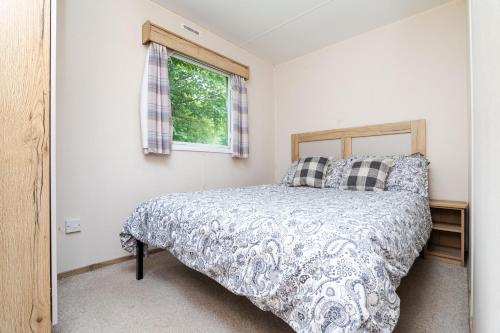 un dormitorio con una cama y una ventana en 3 Bedroom Caravan - Seton Sands, en Port Seton