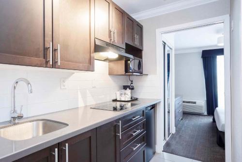 a kitchen with wooden cabinets and a sink and a hallway at Sandman Signature Prince George Hotel in Prince George