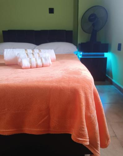 a bed with an orange blanket on top of it at The Green House in Adelianos Kampos