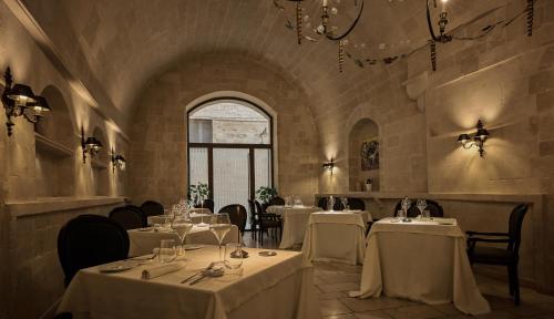 a restaurant with white tables and chairs and a window at Palazzo Gattini Luxury Hotel - VRetreats in Matera