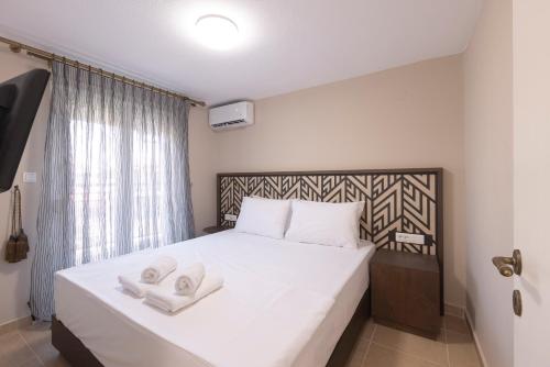 a bedroom with a white bed with two towels on it at Roula's Residence in Flogita